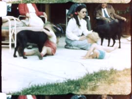 Home movie of Erickson family visit with children and puppies playing together on patio